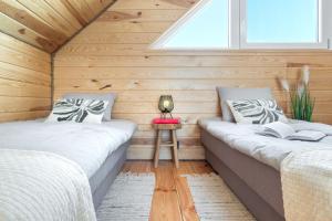 two beds in a room with wooden walls and a window at Warmia Forest Kobułty 