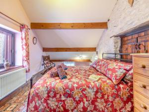 a bedroom with a red bed and a stone wall at Yr Hen Efail in Abergorlech