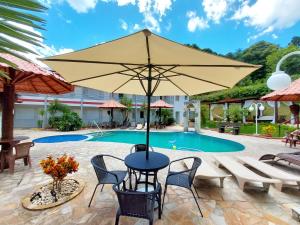 a patio with a table and chairs and an umbrella at Pousada Pompeia in Socorro