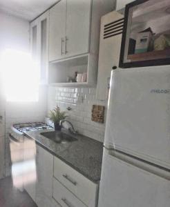 una cucina con frigorifero bianco e lavandino di Casa Deco con Pileta, Asador y Cochera a Córdoba