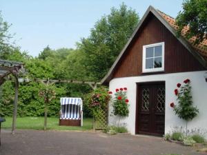 a house with a chair and a door and flowers at Ferienhof Jens Ferienwohnung 3 in Kronsgaard
