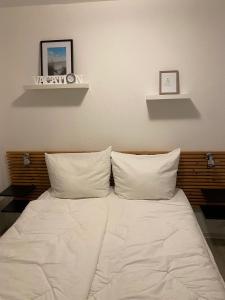 a bed with white sheets and two pillows at Lütje in Greetsiel