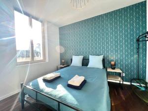 1 dormitorio con 1 cama azul y 2 toallas en La Ribaudière Maison de ville à 5 min Futuroscope, en Chasseneuil-du-Poitou
