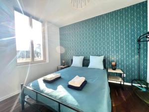 a bedroom with a blue bed with two towels on it at La Ribaudière Maison de ville à 5 min Futuroscope in Chasseneuil-du-Poitou