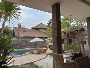 a patio with chairs and a pool in front of a house at Matahari Inn in Gili Trawangan