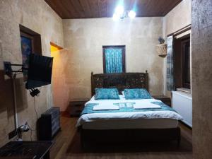 ネヴシェヒルにあるLovely Cappadocia Hotelのベッドルーム(青い枕とテレビ付)