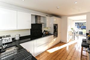 a kitchen with white cabinets and a wooden floor at Garden Apartment with hot tub in Bath