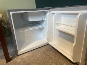 un frigorifero vuoto con la porta aperta in una stanza di Cotswold Retreat - Private & Peaceful 