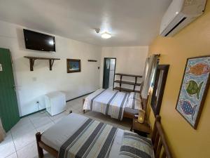a bedroom with two beds and a tv on the wall at Pousada Beleza Pura na Praia da Ferrugem in Garopaba +39 photos