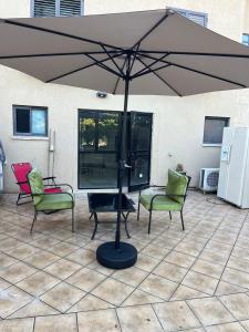 a large umbrella on a patio with chairs and tables at סוויטה במושב פסטורלי רומנטי ושקט in Gannot Hadar