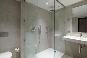 a bathroom with a glass shower and a sink at Van der Valk Hotel Hengelo in Hengelo