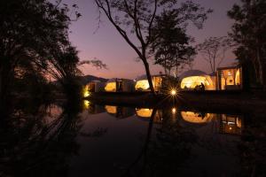 uma vista nocturna para um grupo de tendas junto a um rio em The Chamuang Forest em Ban Dong