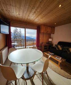 ein Wohnzimmer mit einem Tisch und Stühlen sowie einem Balkon in der Unterkunft Le 1954 La Rosière in Montvalezan