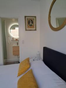 a bedroom with a bed with yellow pillows and a mirror at Agréable 2 pièces - rue du vieux Versailles in Versailles