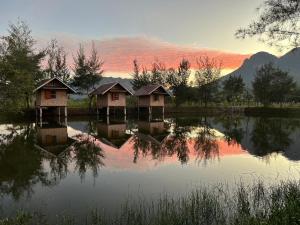 a group of huts on a lake at sunset at Numpu Baandin in Sam Roi Yot