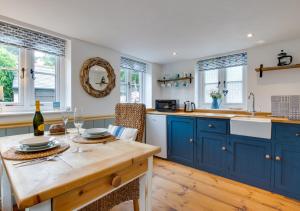 a kitchen with blue cabinets and a wooden table at Pendeen Hayloft in Saint Stephen