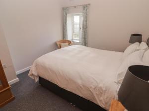 a bedroom with a white bed and a window at The Granary in Kilgetty