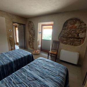 a bedroom with two beds and a chair and a stone wall at Istanti - Menta in Costigliole Saluzzo