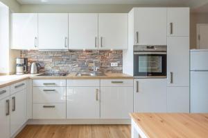 una cocina con armarios blancos y una pared de ladrillo en Wolke 7, en Husum
