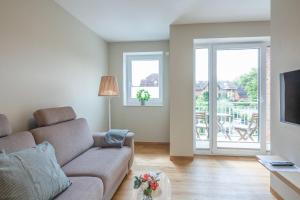 Una sala de estar con un sofá y dos ventanas. en Wolke 7, en Husum