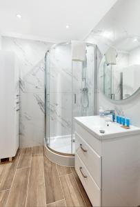 a white bathroom with a shower and a sink at Poznań Airport Comfy Apartment in Poznań