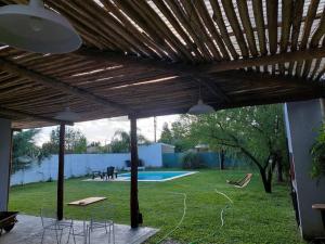 a patio with a wooden pergola and a pool at Casa en Funes. Pileta, Parrilla & Parque. in Funes