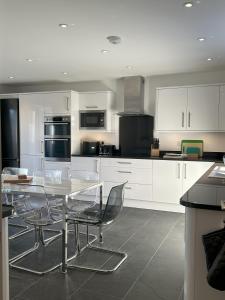 een keuken met witte kasten en een tafel en stoelen bij Whitebridge Cottage in Swansea