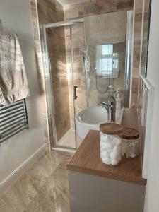 een badkamer met een douche, een wastafel en een bad bij Whitebridge Cottage in Swansea