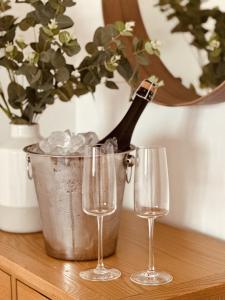 eine Flasche Champagner in einem Eimer neben zwei Weingläsern in der Unterkunft Whitebridge Cottage in Swansea