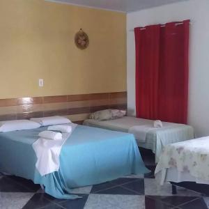 a room with two beds and a red curtain at pousada chykos in Barreirinhas