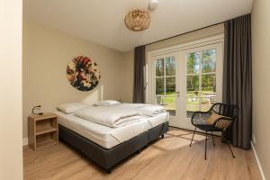 1 dormitorio con 1 cama, 1 silla y 1 ventana en 't Borghuis, en Losser
