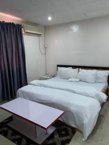 a hotel room with two beds and a table at Arena Guest House and Lounge in Ikeja