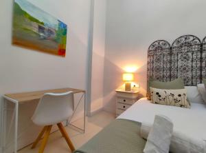 a bedroom with a bed and a desk and a chair at Aponte Suites in Seville