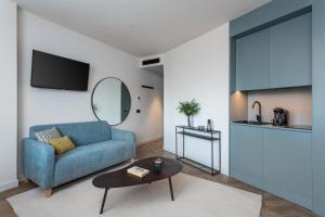 a living room with a blue couch and a table at Aparthotel Tribunal in Madrid