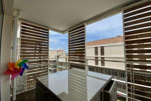a balcony with a table and a large window at Le Terrasse en Mer- Air conditioning parking and seaside! in Palavas-les-Flots