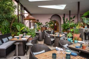 テウル・シュル・メールにあるティアラ ミラマー ビーチ ホテル ＆ スパのテーブルと椅子、植物のあるレストラン