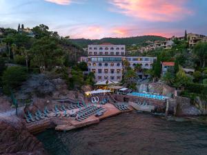 a resort with a pool and lounge chairs in the water at Tiara Miramar Beach Hotel & Spa in Théoule-sur-Mer