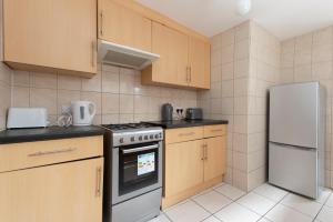 a kitchen with wooden cabinets and a stove and refrigerator at 4 BED House IN Dartford 8 Beds Sleeps 10 in Kent