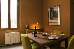 - une table à manger avec des chaises jaunes et une bouteille de vin dans l'établissement Picassiette, à Chartres