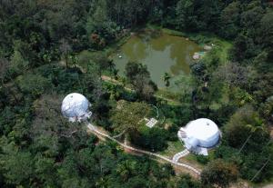 two observatory domes in a forest next to a lake at GeoLux - Luxurious Geodesic Dome in Chikmagalur