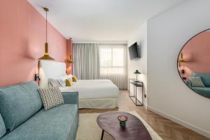 una camera d'albergo con letto, divano e specchio di Aparthotel Tribunal a Madrid