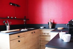 Una cocina con paredes rojas y gabinetes de madera. en Fulbert - view on Cathedral and Place des Epars, en Chartres