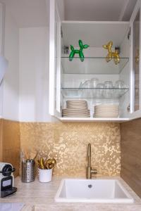 - une cuisine avec un évier et une étagère avec de la vaisselle dans l'établissement LOUVRE-MONTORGEUIL PARIS HISTORICAL CENTER, à Paris