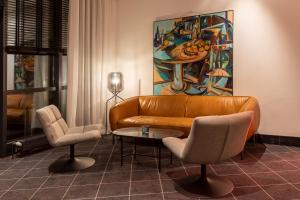 a living room with a couch and chairs and a painting at Precise House Düsseldorf Airport in Ratingen