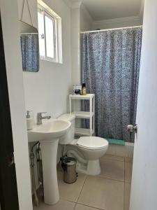 a white bathroom with a toilet and a sink at Departamento Merced in Quillota