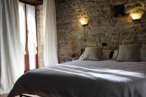 1 dormitorio con 1 cama grande y pared de piedra en Torre di Celle, en Monte Santa Maria Tiberina