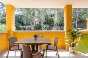 une salle à manger avec des murs jaunes, une table et des chaises dans l'établissement Apartamentos Flor los Almendros, à Paguera