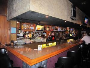 a bar in a restaurant with a man standing at the bar at Travelers INN in West Sacramento