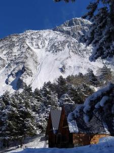 una casa frente a una montaña cubierta de nieve en Cottage Paradise, en Kazbegi