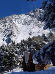 une maison en face d'une montagne enneigée dans l'établissement Cottage Paradise, à Kazbegi